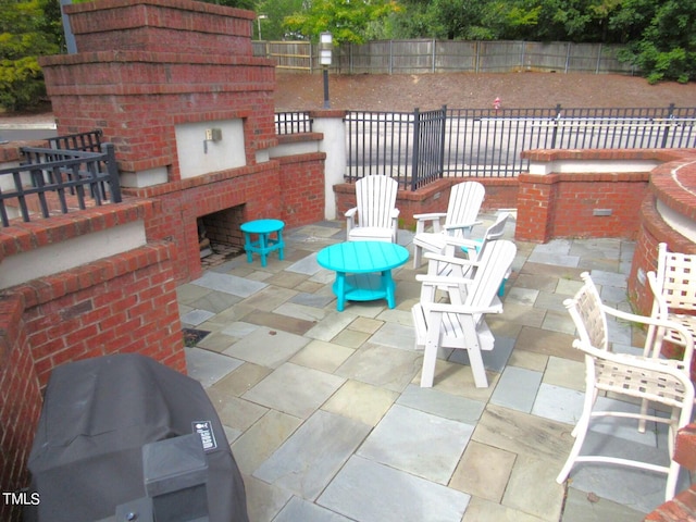 view of patio / terrace featuring an outdoor brick fireplace and area for grilling