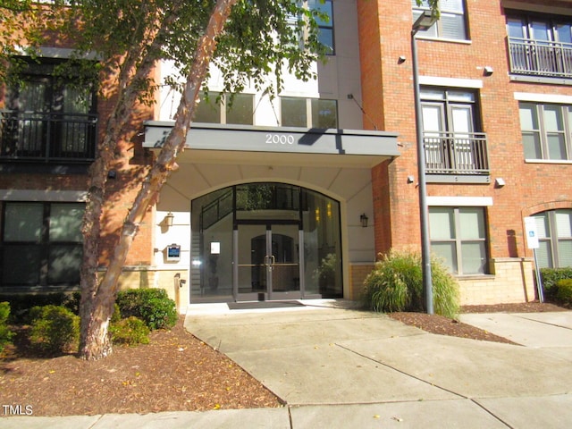 view of exterior entry featuring french doors and a balcony