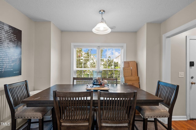 dining area with wood-type flooring and a textured ceiling