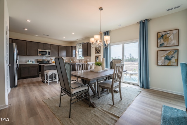 dining area featuring light hardwood / wood-style floors and a chandelier