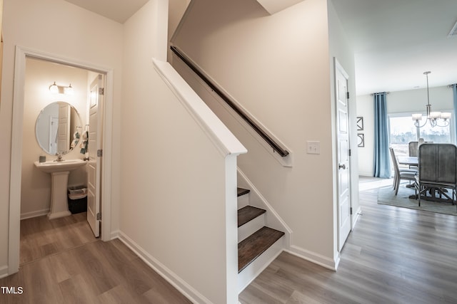 staircase featuring a chandelier, hardwood / wood-style flooring, and sink