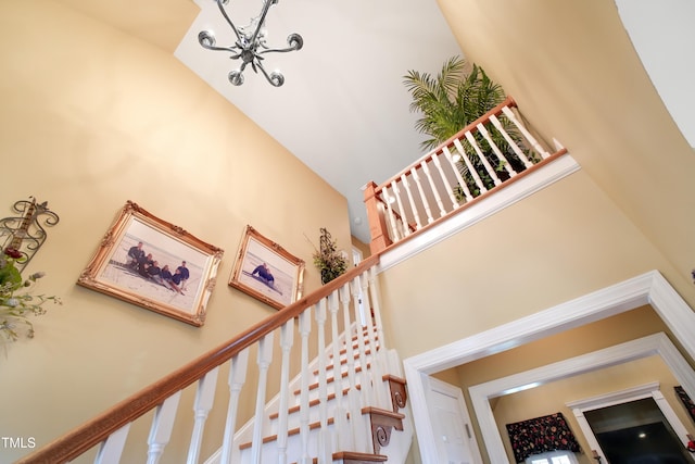 staircase with a notable chandelier and high vaulted ceiling