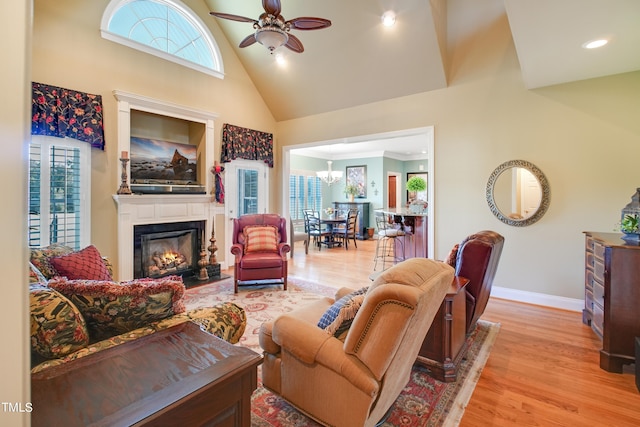 living room with light hardwood / wood-style flooring, high vaulted ceiling, and ceiling fan with notable chandelier