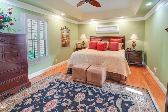 bedroom featuring a raised ceiling, light hardwood / wood-style floors, ornamental molding, and ceiling fan