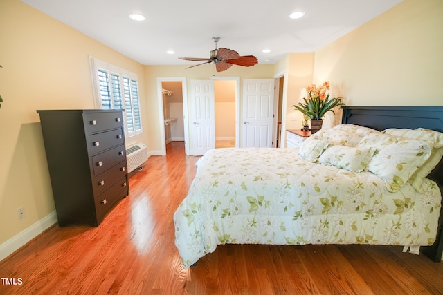 bedroom featuring a spacious closet, an AC wall unit, a closet, ceiling fan, and hardwood / wood-style flooring