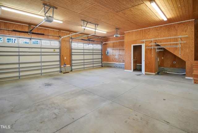 garage featuring wooden walls, a garage door opener, and wood ceiling