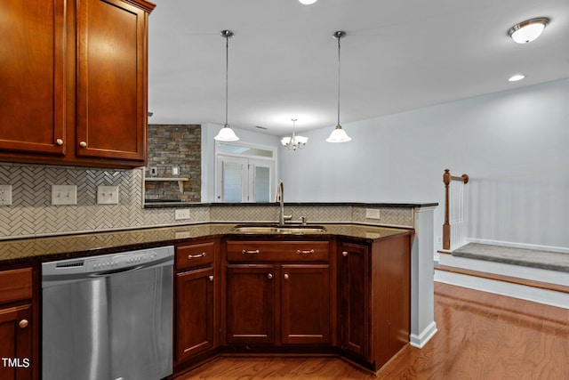 kitchen with tasteful backsplash, light wood-type flooring, hanging light fixtures, sink, and stainless steel dishwasher