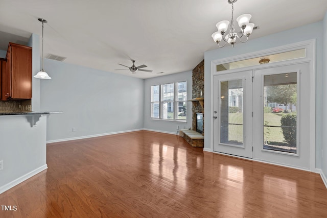 unfurnished living room with a fireplace, wood-type flooring, and ceiling fan with notable chandelier