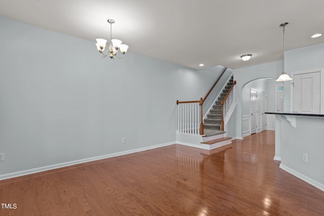 unfurnished living room featuring a chandelier and wood-type flooring