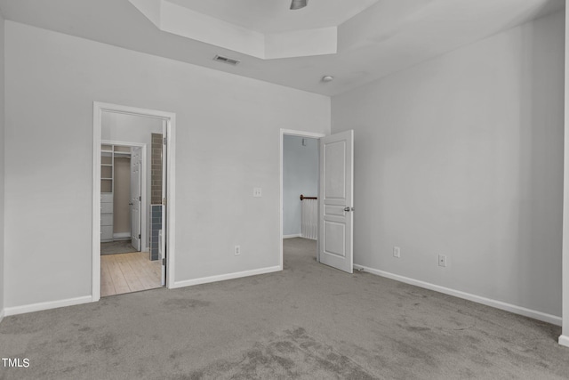 unfurnished bedroom with a closet, a spacious closet, and light colored carpet