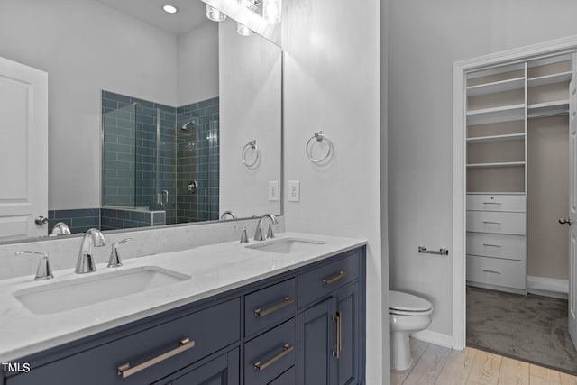 bathroom with hardwood / wood-style floors, a shower with door, vanity, and toilet