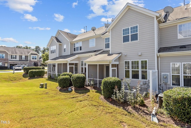 view of front of home with a sunroom, central AC, and a front lawn