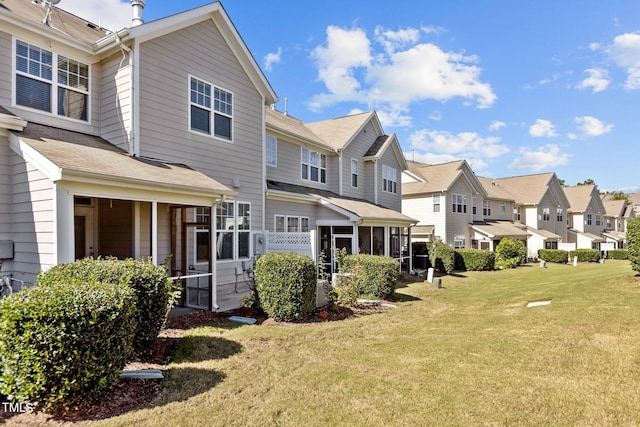 rear view of house with a sunroom and a yard