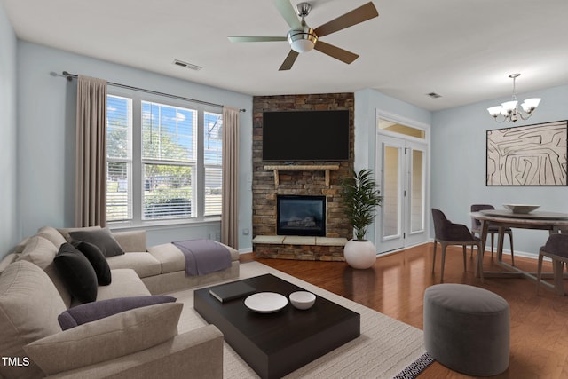 living room featuring hardwood / wood-style floors, a fireplace, and ceiling fan with notable chandelier