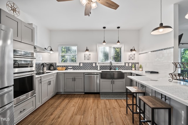 kitchen with decorative light fixtures, stainless steel appliances, sink, and a wealth of natural light