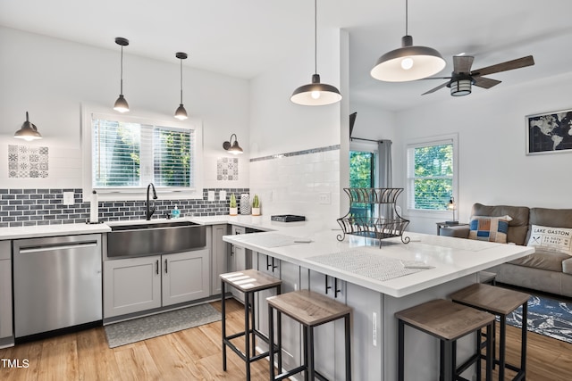 kitchen with a kitchen breakfast bar, a wealth of natural light, dishwasher, and sink