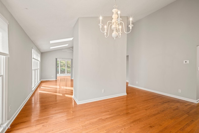 interior space featuring vaulted ceiling with skylight, light hardwood / wood-style floors, and a notable chandelier