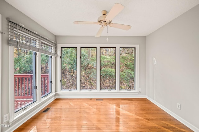 unfurnished sunroom featuring ceiling fan and a wealth of natural light