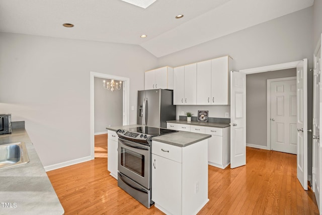 kitchen with white cabinets, a center island, stainless steel appliances, and lofted ceiling