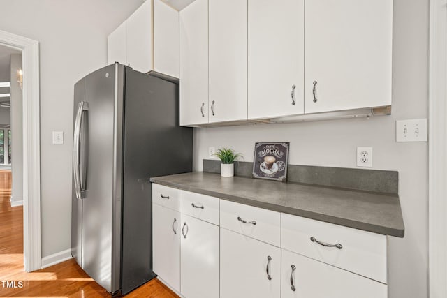 kitchen with stainless steel fridge, white cabinets, and light wood-type flooring