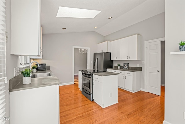 kitchen with appliances with stainless steel finishes, light hardwood / wood-style flooring, white cabinetry, and lofted ceiling with skylight