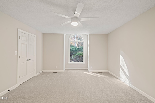 carpeted spare room featuring a textured ceiling and ceiling fan