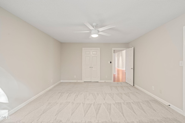 unfurnished room with ceiling fan, light carpet, and a textured ceiling