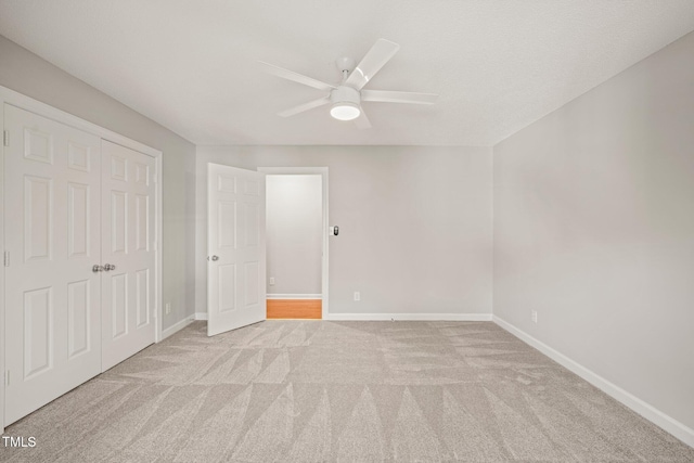 unfurnished bedroom featuring ceiling fan, light colored carpet, and a closet