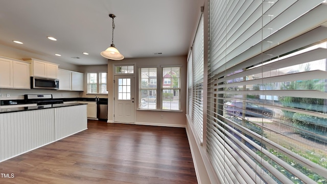 kitchen featuring appliances with stainless steel finishes, white cabinetry, dark hardwood / wood-style flooring, and pendant lighting