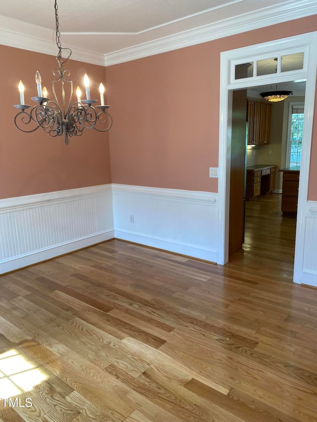 unfurnished room featuring a chandelier, hardwood / wood-style flooring, and crown molding