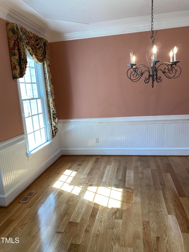 unfurnished room with crown molding, light hardwood / wood-style floors, and a notable chandelier