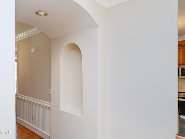 hall with light wood-type flooring and ornamental molding