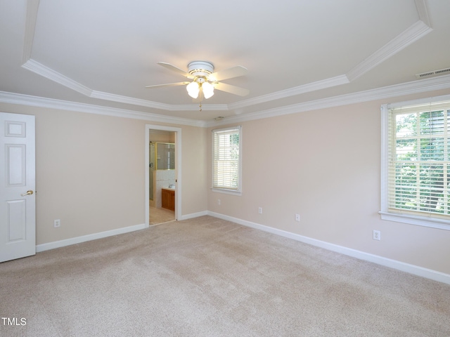 carpeted empty room with a raised ceiling, a wealth of natural light, ornamental molding, and ceiling fan