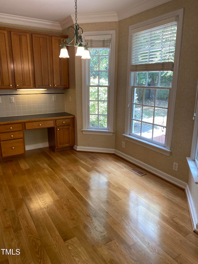 kitchen with pendant lighting, built in desk, tasteful backsplash, and plenty of natural light