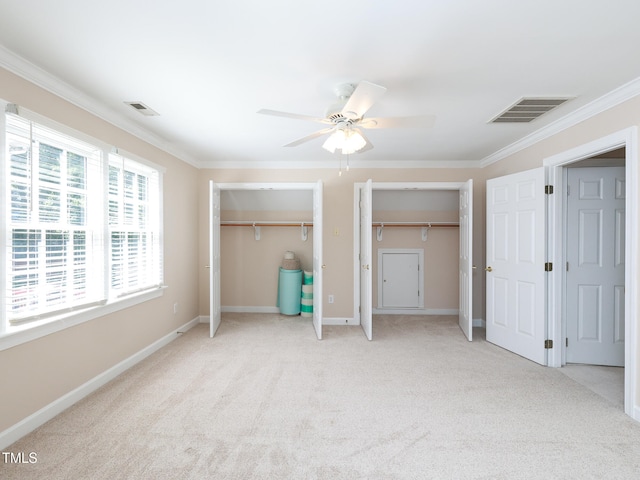 unfurnished bedroom with multiple closets, ceiling fan, crown molding, and light colored carpet