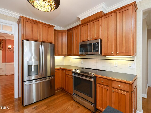 102 Preston Pines Dr, Cary, NC 27513 - kitchen featuring appliances with stainless steel finishes, ornamental molding, wood finished floors, decorative backsplash, and dark countertops