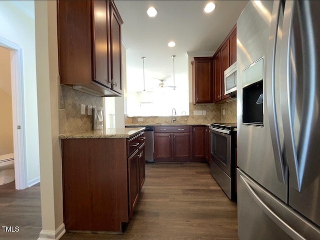 kitchen featuring pendant lighting, sink, dark hardwood / wood-style floors, light stone countertops, and appliances with stainless steel finishes