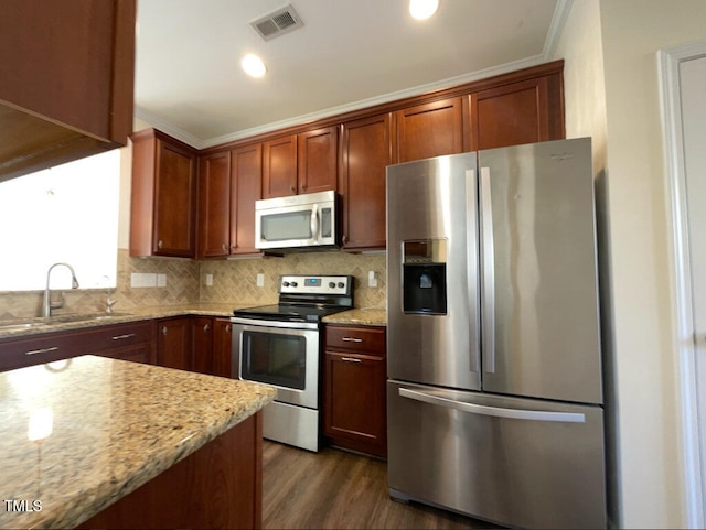 kitchen with stainless steel appliances, light stone counters, ornamental molding, and sink