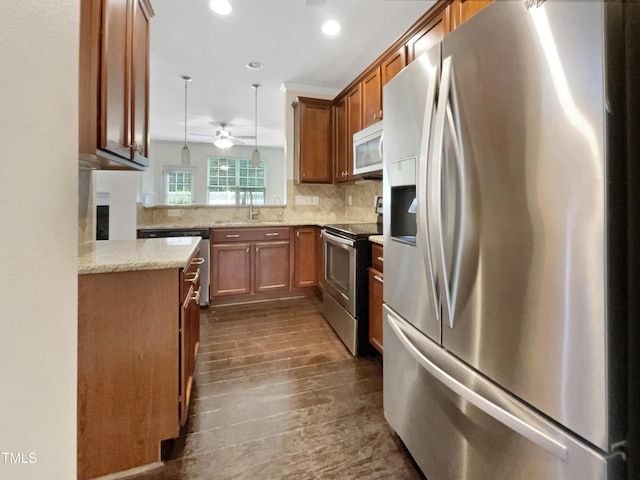 kitchen with dark hardwood / wood-style flooring, kitchen peninsula, pendant lighting, decorative backsplash, and appliances with stainless steel finishes