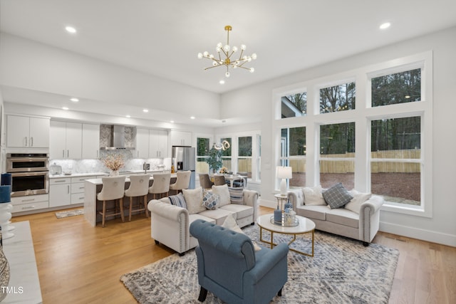 living room with a notable chandelier, a high ceiling, and light hardwood / wood-style floors