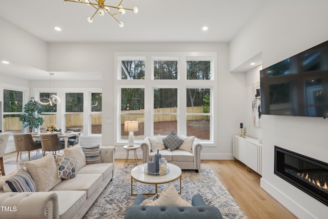 living room with a high ceiling, light hardwood / wood-style floors, and a notable chandelier