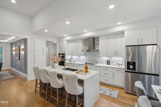 kitchen featuring sink, wall chimney exhaust hood, white cabinetry, stainless steel refrigerator with ice dispenser, and light wood-type flooring