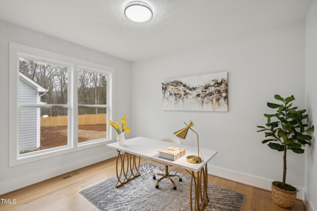 office with a healthy amount of sunlight and hardwood / wood-style flooring