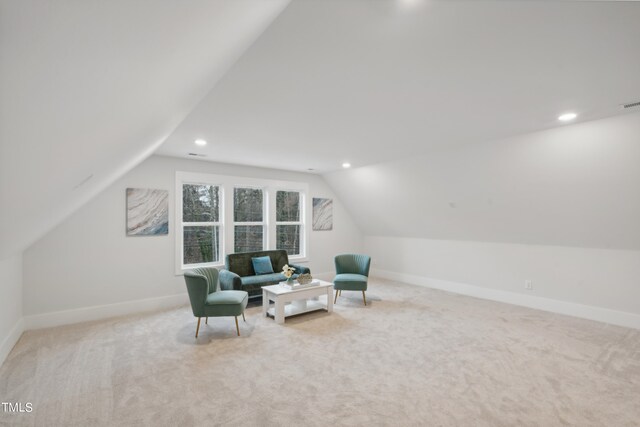 living area featuring vaulted ceiling and light colored carpet