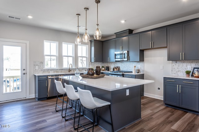 kitchen featuring appliances with stainless steel finishes, a kitchen island, and dark wood-type flooring