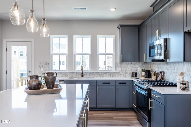 kitchen featuring appliances with stainless steel finishes, backsplash, dark wood-type flooring, sink, and hanging light fixtures