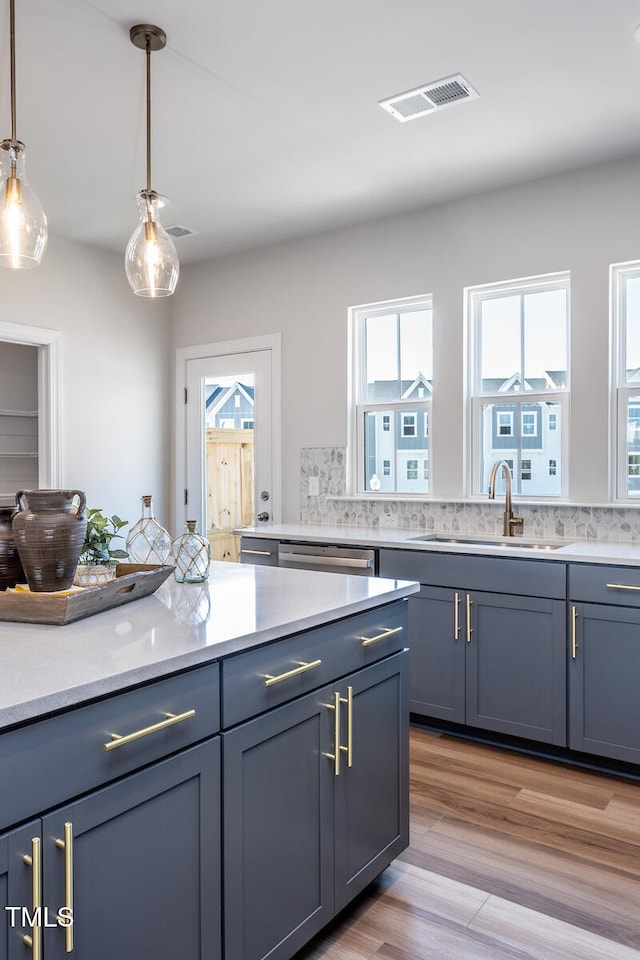 kitchen with pendant lighting, backsplash, light hardwood / wood-style flooring, and sink