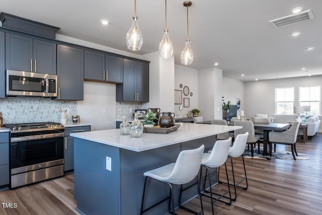 1206 Holding Village Way, Wake Forest, NC 27587 - kitchen featuring stainless steel appliances, open floor plan, dark wood-type flooring, a kitchen bar, and light countertops