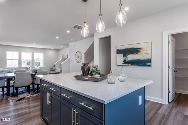 kitchen with blue cabinetry, a kitchen island, dark wood-type flooring, and hanging light fixtures