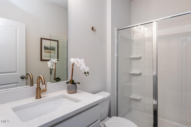 bathroom with vanity, a shower with shower door, and toilet